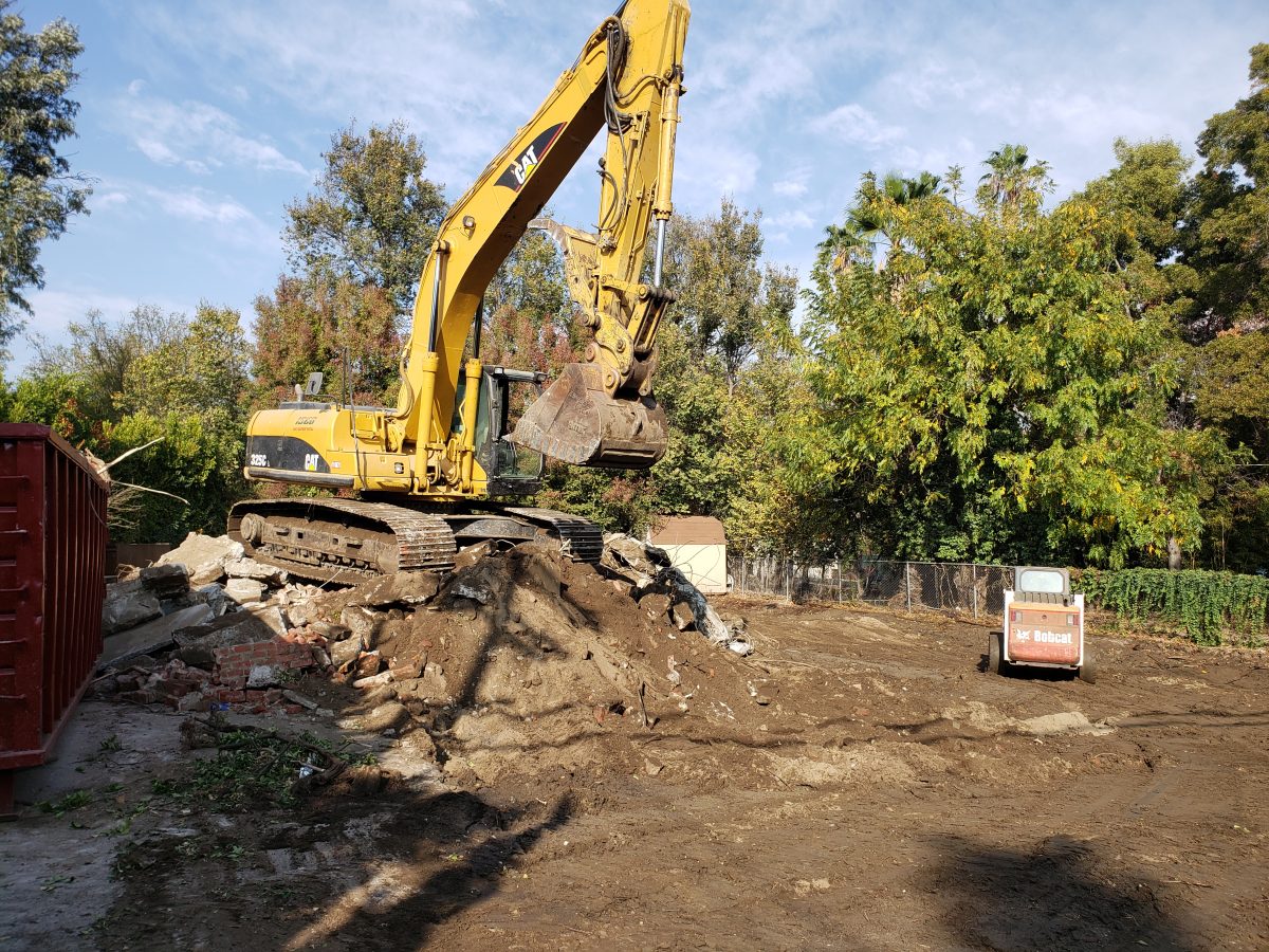 excavator clearing a wooded lot, prepping raw land for construction